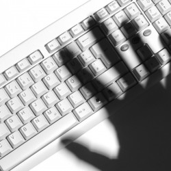 Shadow of a human hand over a computer keyboard