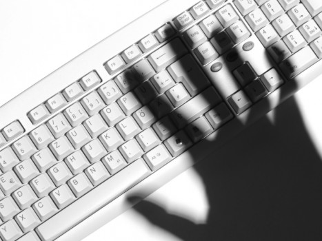Shadow of a human hand over a computer keyboard