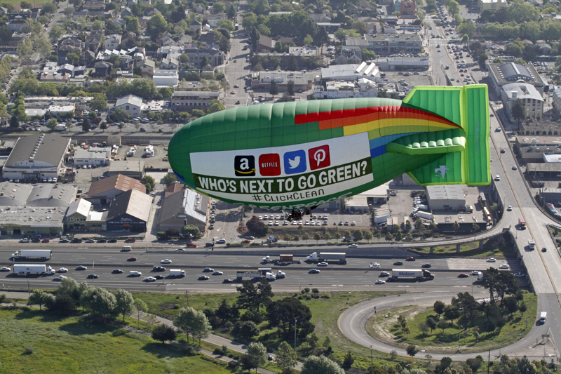 The Greenpeace thermal airship A.E. Bates flies over the East Bay area near Oakland, Calif., with a banner on one side displaying the logos of Apple, Facebook and Google and the message "Powering A Greener Internet." The other side of the aircraft the banner reads "Who's next to go Green? #ClickClean" with the logos of Amazon, Netflix, Twitter and Pinterest.