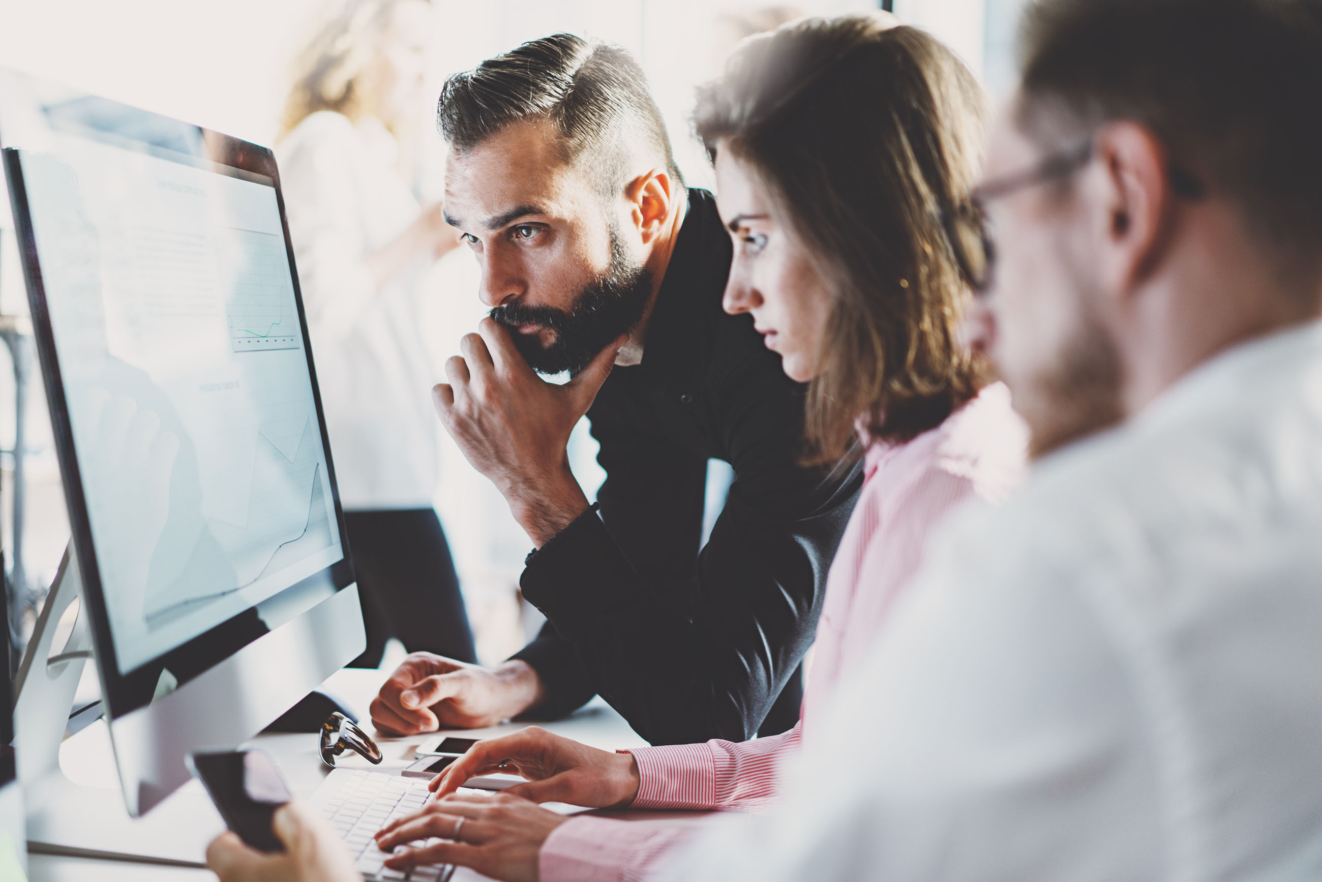 Teamwork concept.Young creative coworkers working with new startup project in modern office.Group of three people analyze data on desktop computer.Horizontal,blurred background; Shutterstock ID 583869832