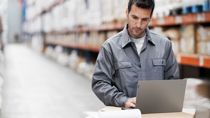 A young man using his notebook and checking his notes while working in a warehouse