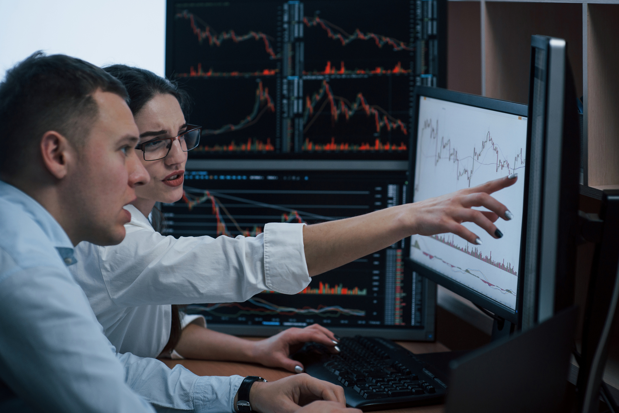 Looks like we must achieve that line. Team of stockbrokers are having a conversation in a office with multiple display screens