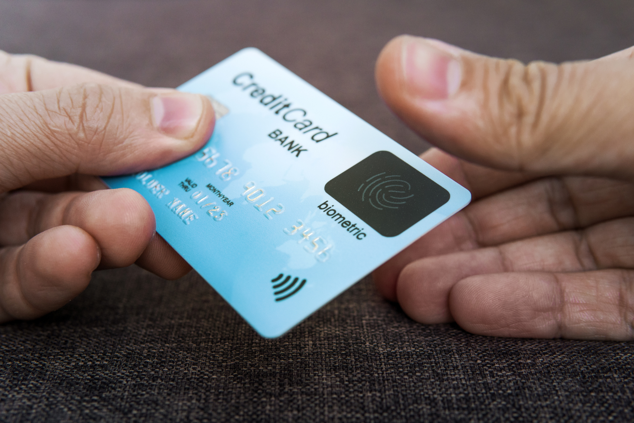 Credit card has built-in fingerprint scanner. Illustration of biometric payment security. One male hand is holding blue card and other touching scanner with thumb.