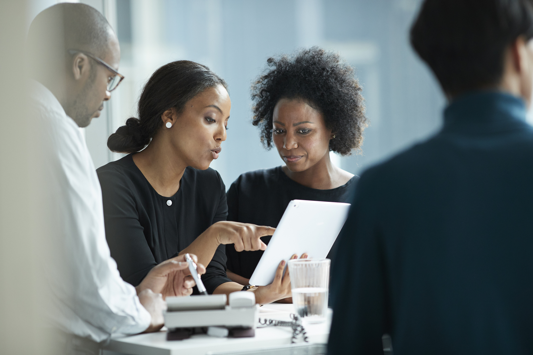 Group of co-workers standing around desk and having meeting