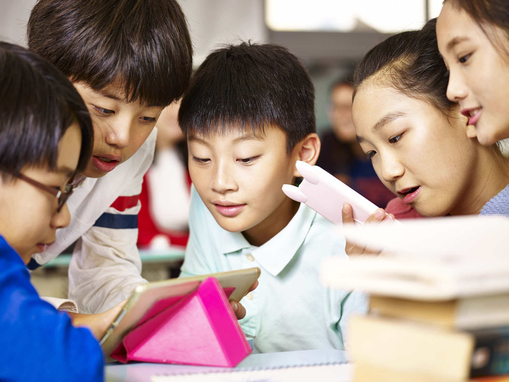 asian elementary school children playing with digital tablet during break