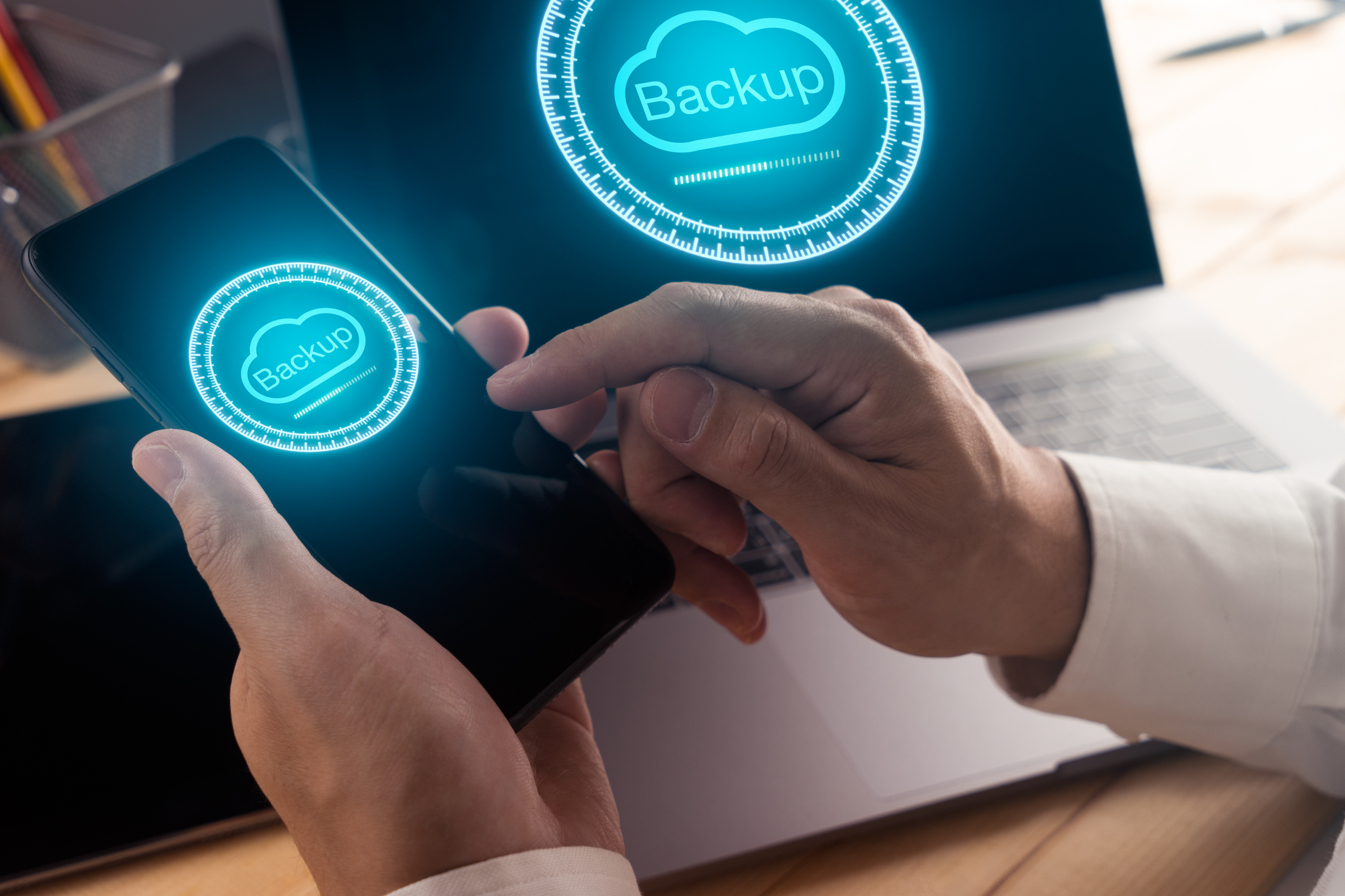 Businessman hand using smart phone and modern laptop computer with Cloud backup technology