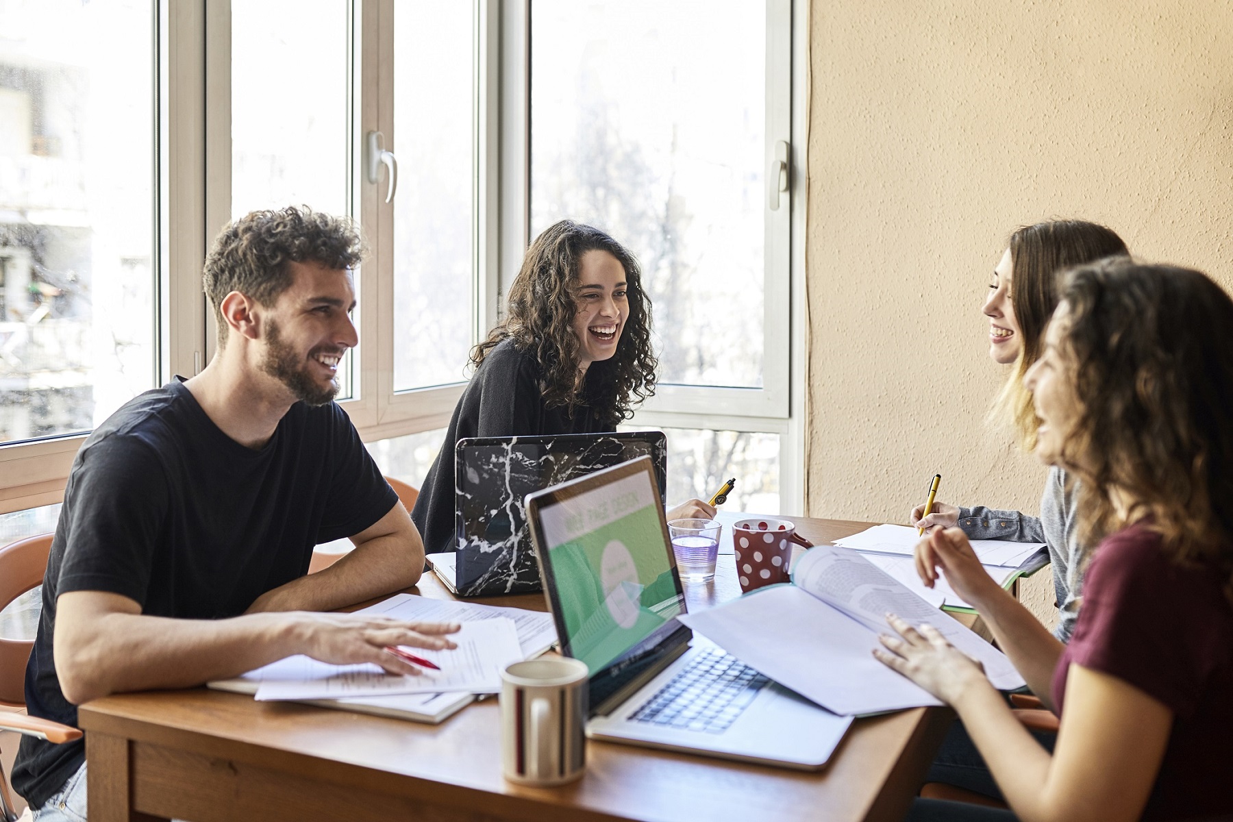 Four happy students at desk learning together