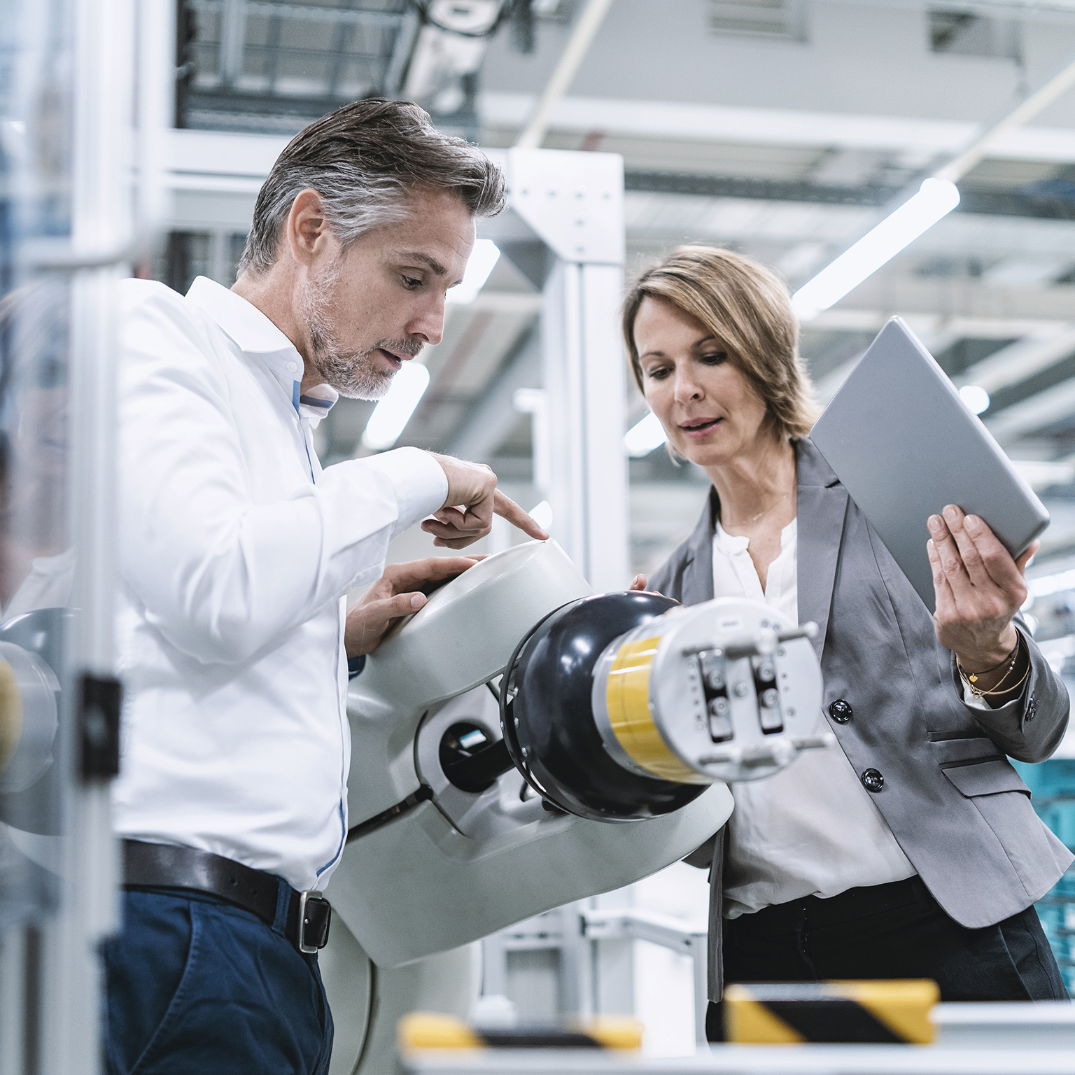 Businesswoman and man talking at assembly robot in a factory