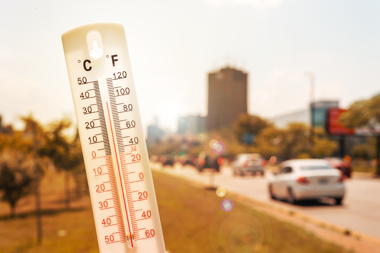 Thermometer in front of cars and traffic during heatwave