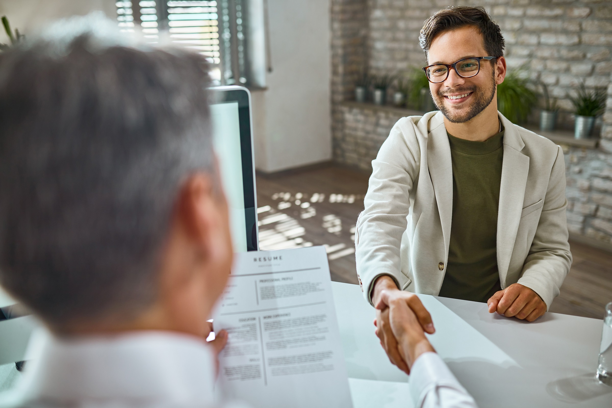 Young happy man shaking hands with a businessman on a job interv