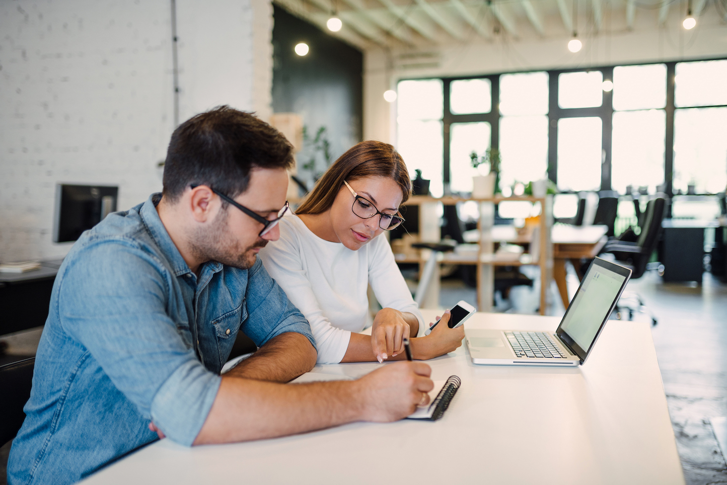 Two young colleagues working in modern open-space office.