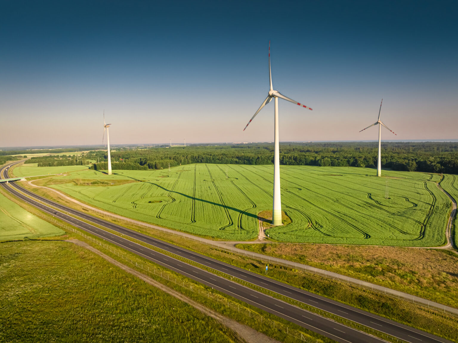 Wind turbines and green field near highway, aerial view